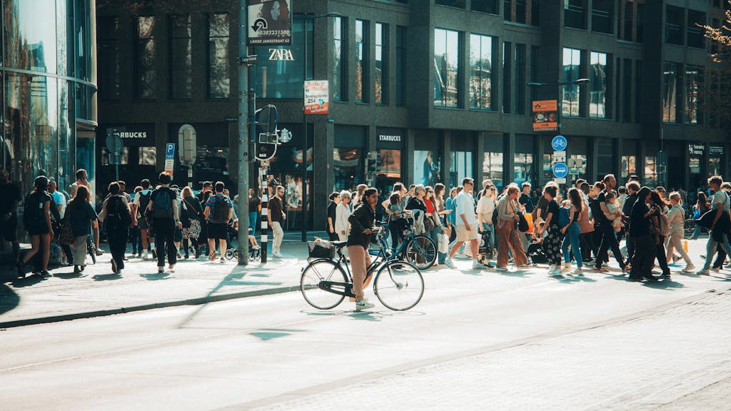 A bustling Utrecht street with a cyclist and pedestrians crossing in the summer.