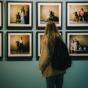 Back view of a woman observing framed art in a modern museum gallery.